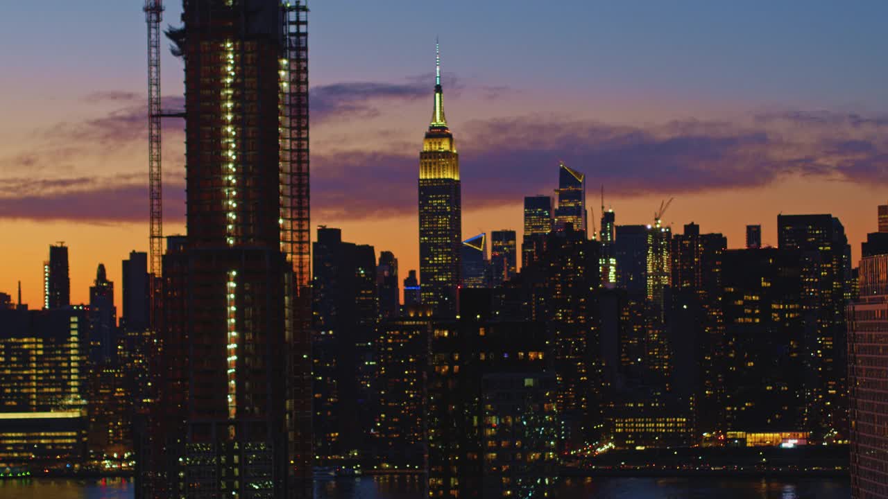 从皇后区鸟瞰曼哈顿中城，俯瞰长岛市海滨的豪华住宅楼，在黄昏时分，天空被戏剧化地照亮。无人机视频与向后相机运动。视频下载