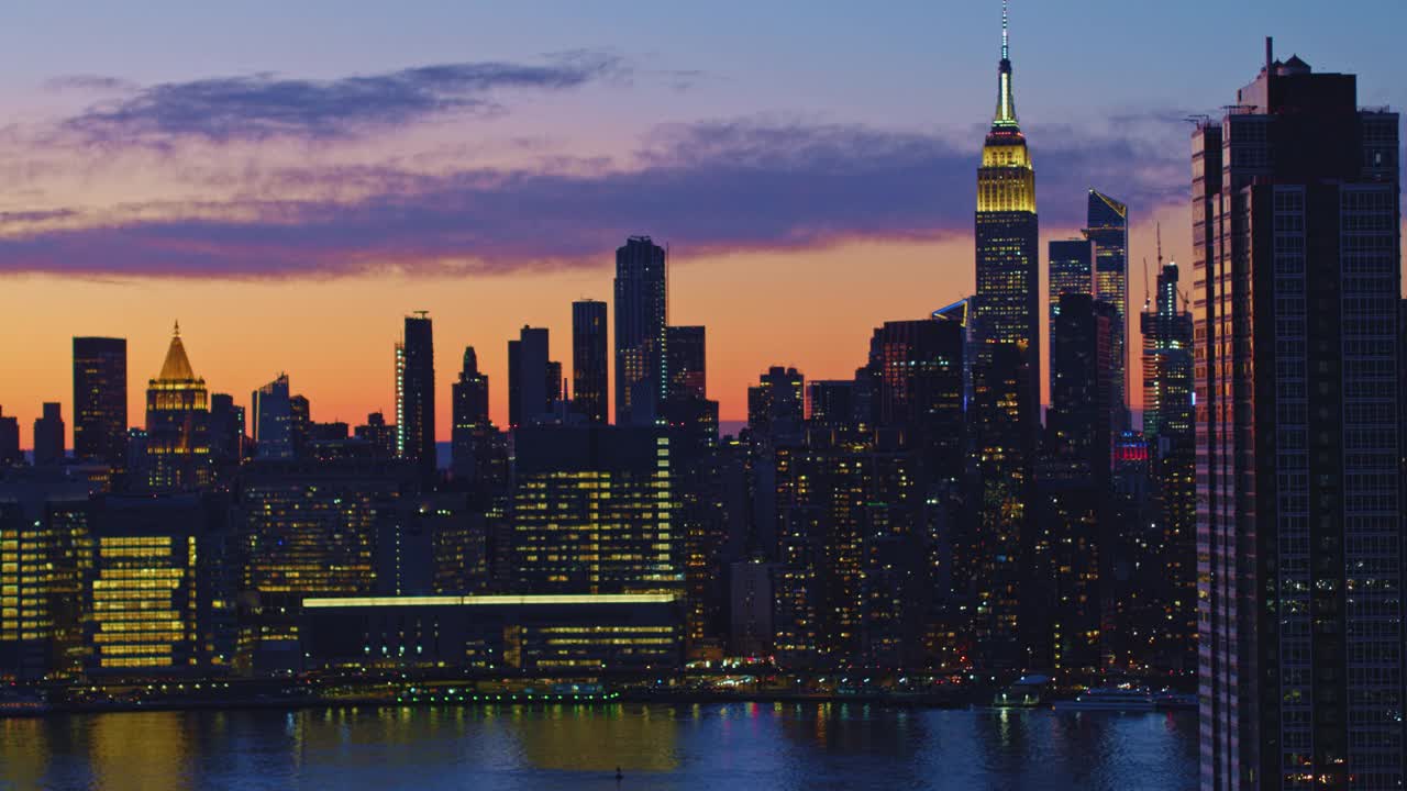 从皇后区鸟瞰曼哈顿中城，俯瞰长岛市海滨的豪华住宅楼，在黄昏时分，天空被戏剧化地照亮。无人机视频与平移摄像机运动。视频下载