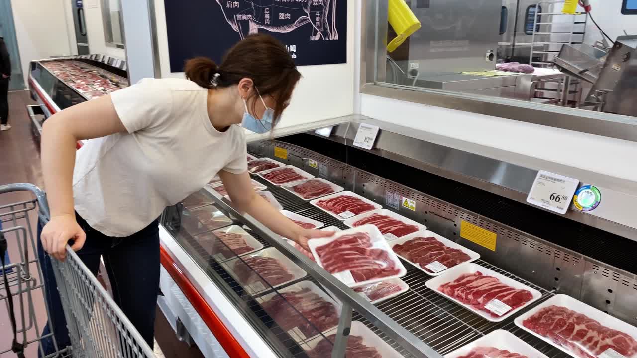 亚洲妇女戴着口罩在超市买肉视频素材