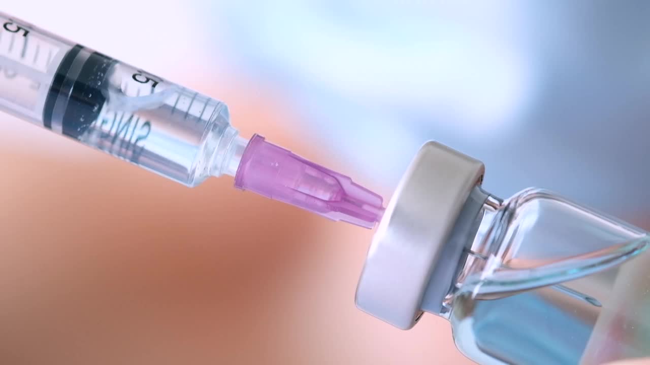在医院里，医生手里拿着一个注射器和一个蓝色的疫苗瓶。健康和医学概念。慢动作镜头视频素材