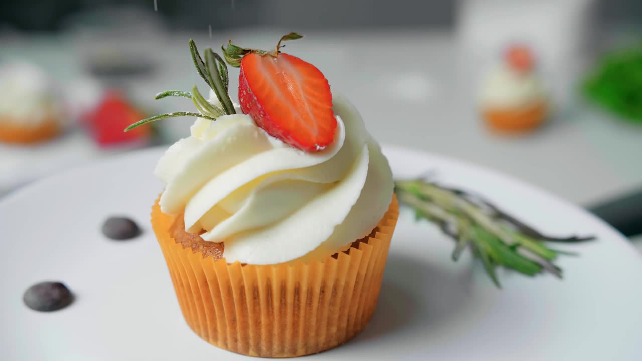 甜点厨师女手装饰美味的纸杯蛋糕白奶油顶部切草莓块在厨房视频素材