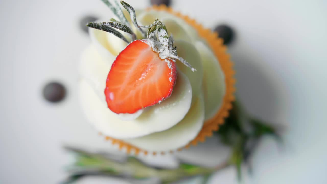 甜点厨师女手装饰美味的纸杯蛋糕白奶油顶部切草莓块在厨房视频素材