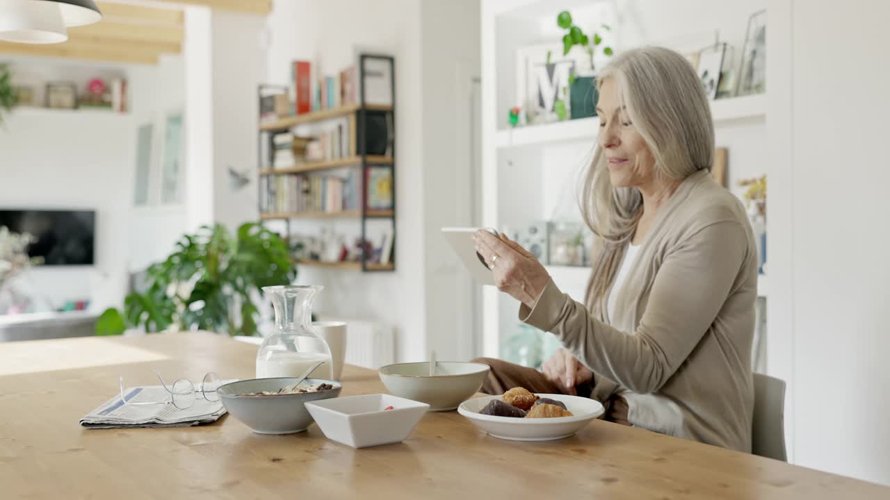 资深白人妇女享受视频通话在早餐视频素材