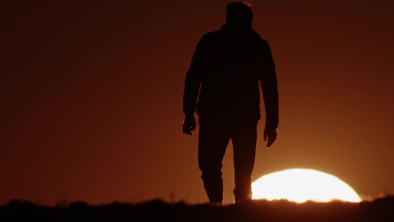 黄昏时分，一个农民走在田野上的剪影。视频下载