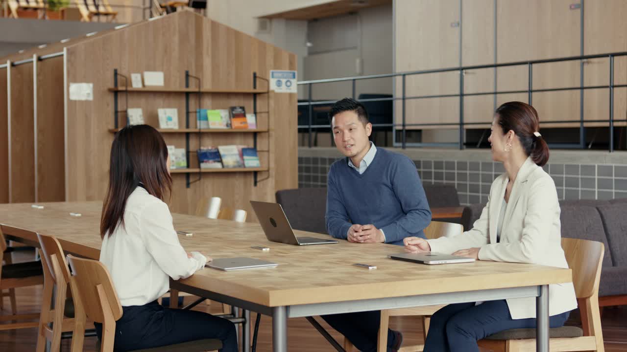 三个同事在一个现代化的办公室里一起工作视频下载