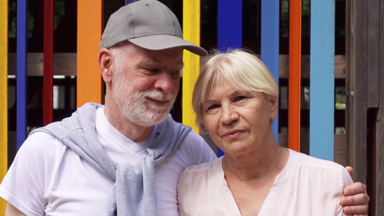 一对微笑的老年夫妇站在彩色的墙壁背景下。无忧无虑的旅游家庭享受假期视频下载
