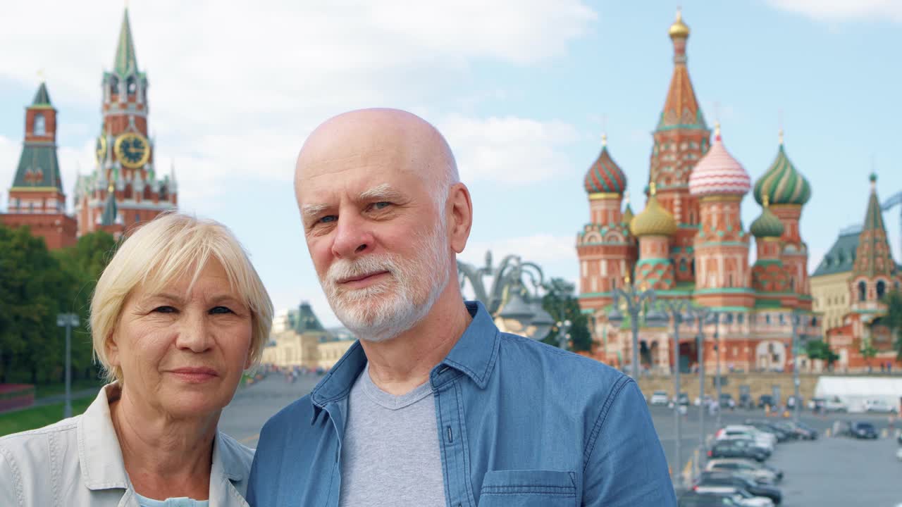 一对老年夫妇站在俄罗斯莫斯科圣巴西尔大教堂和克里姆林宫钟楼的背景上视频下载