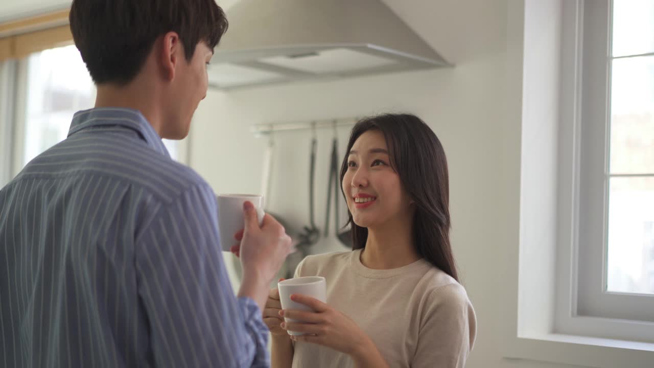 夫妇-年轻的男人和年轻的女人拿着杯子聊天视频素材