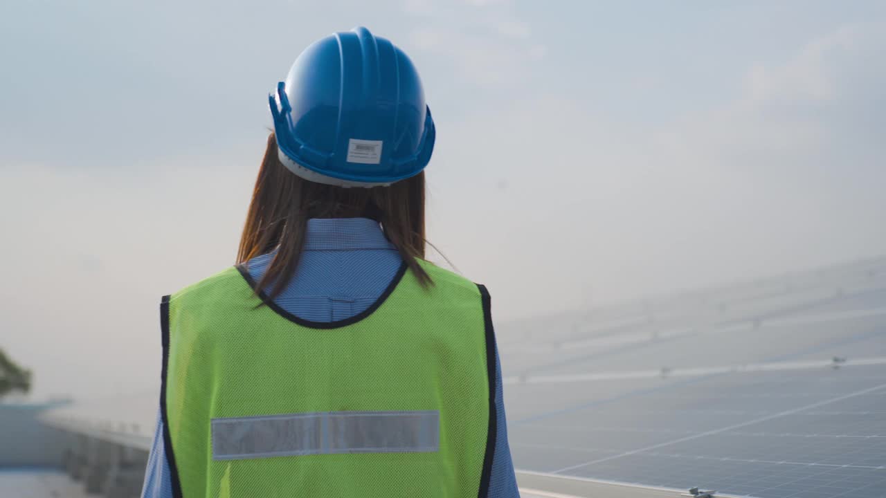 穿着制服的亚洲女工程师在一台收音机上讲话，并检查太阳能发电厂的光伏装置视频素材