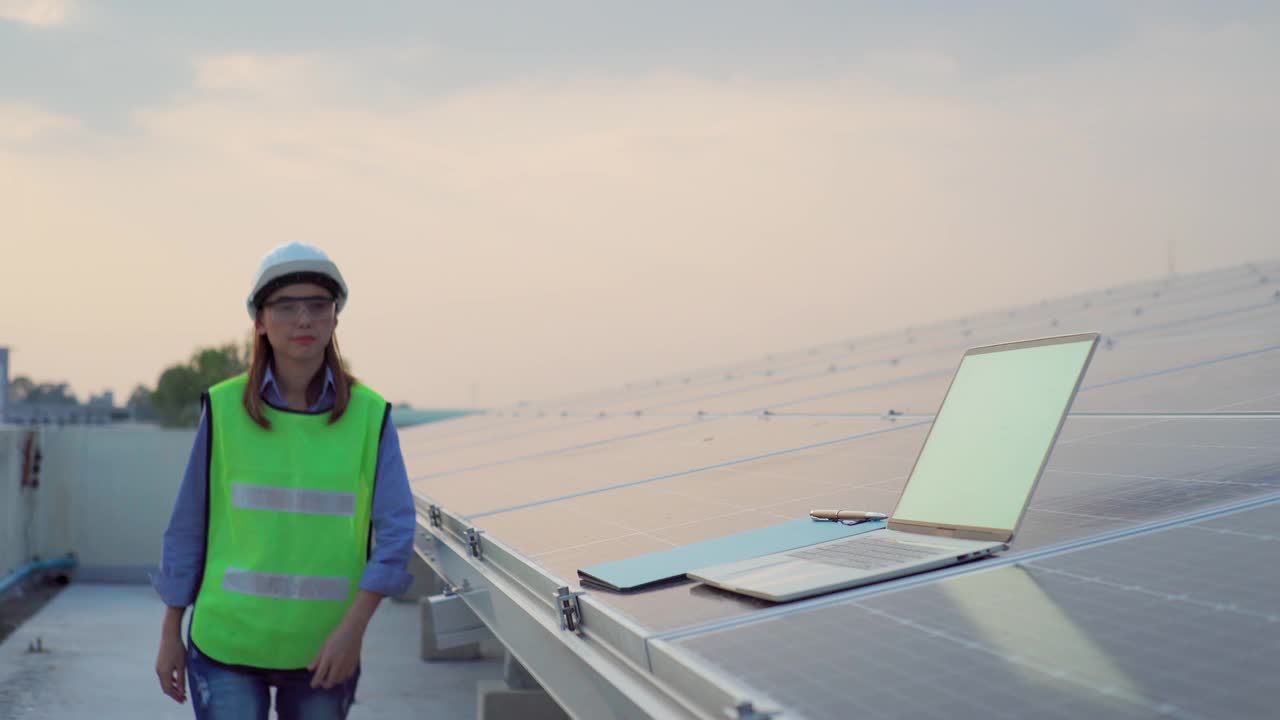 穿着制服的亚洲女工程师，在太阳能电池板厂用笔记本电脑工作视频素材