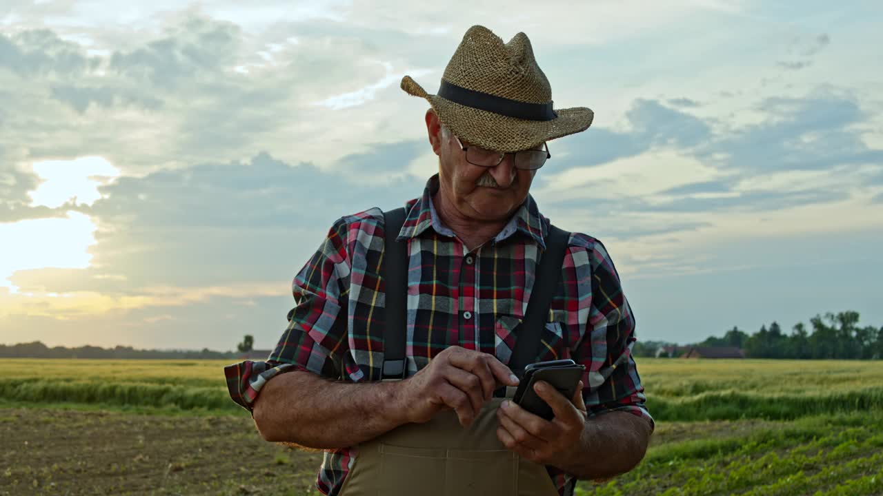 在田里工作时使用智能手机的资深农民视频下载