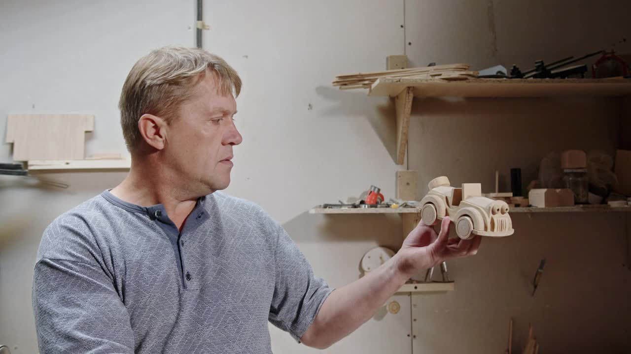 一名熟练的木匠为他的孙子做了一辆木制汽车，他仔细检查了家庭车间里的木制玩具，并想创建一个创业公司视频素材