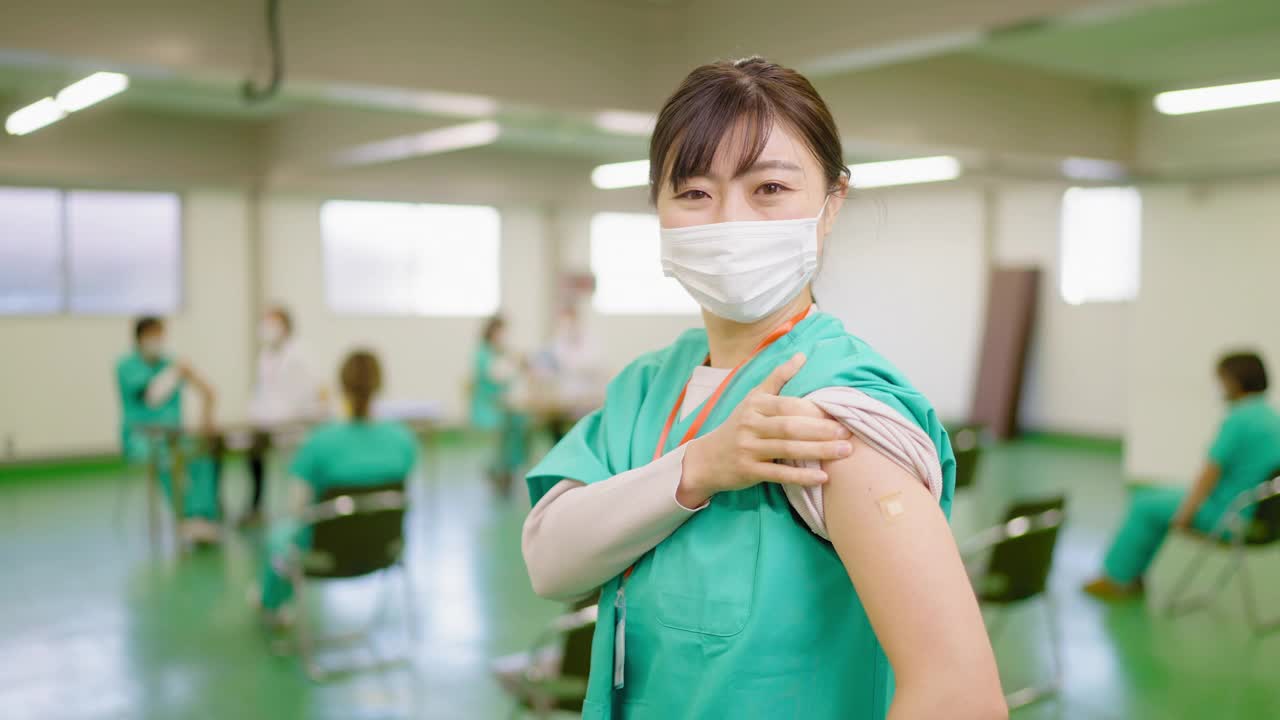 快乐的前线医护人员在接种疫苗后微笑着向镜头展示她的手臂视频下载