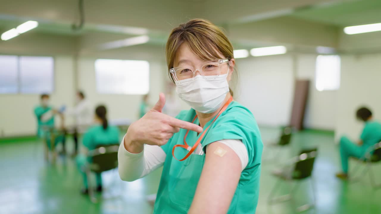 在接种疫苗后，快乐的前线医护人员向镜头展示她的手臂和微笑视频下载