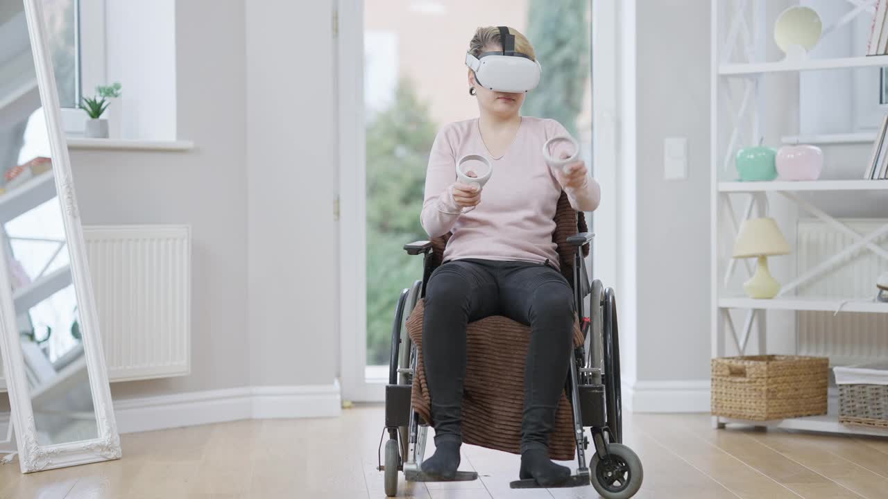 宽镜头肖像残疾的年轻女子在轮椅玩视频游戏在慢动作使用VR头盔和运动控制器。残疾人在家享受虚拟增强现实。视频下载