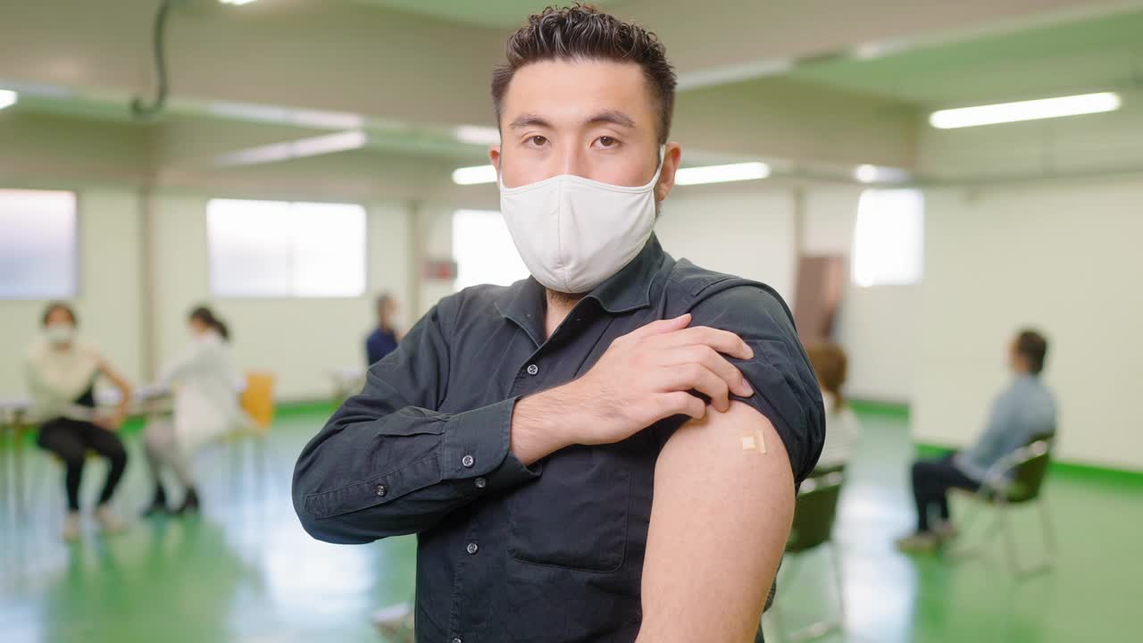 在接种疫苗后，一个快乐的男人向镜头展示他的手臂和微笑视频素材