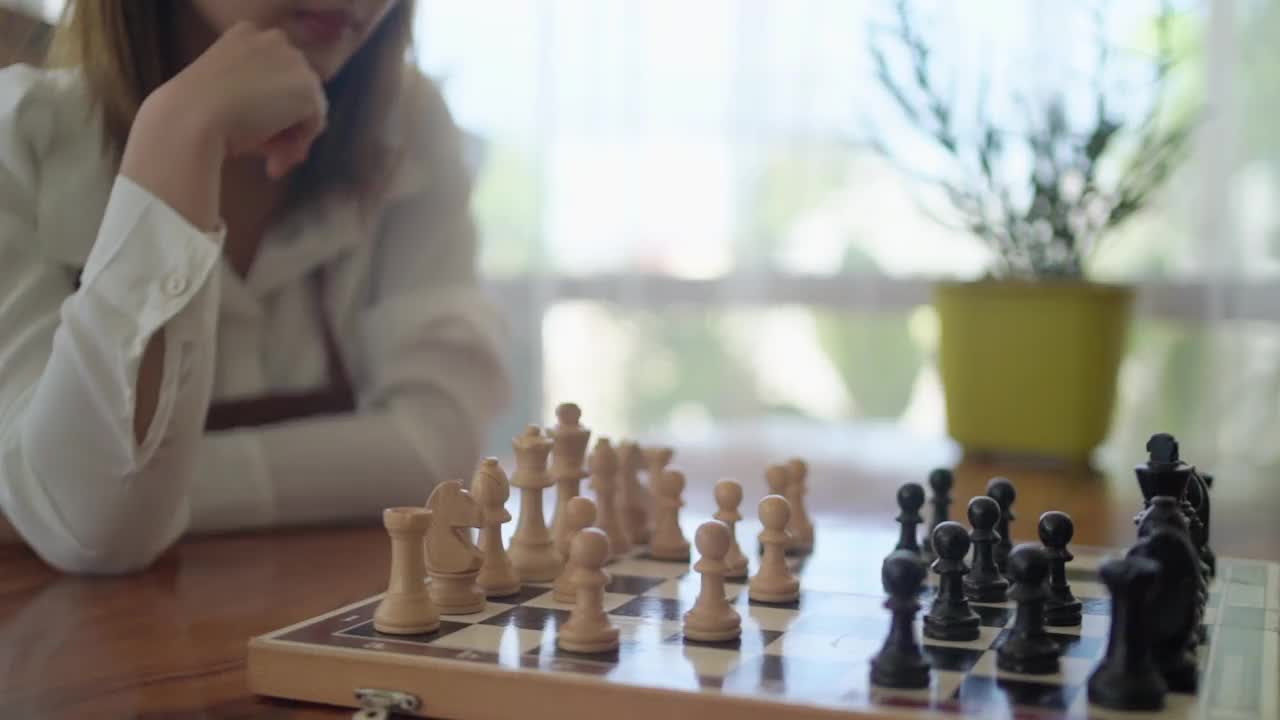 一名年轻的亚洲妇女在下棋时戴着口罩以预防COVID - 19。视频下载