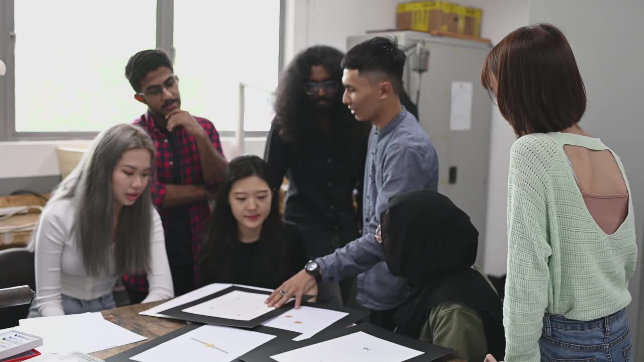亚裔马来男教师反馈检查他的学生珠宝设计工作在大学教室视频素材