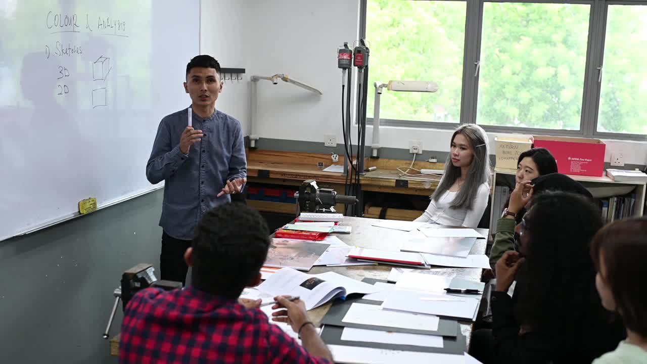 亚裔马来男讲师在教室里用白板给他的学生讲授珠宝设计课程视频素材