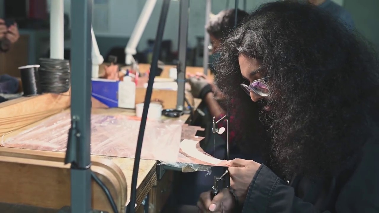 侧视图非洲亚裔男学生在大学工作台使用手锯视频素材