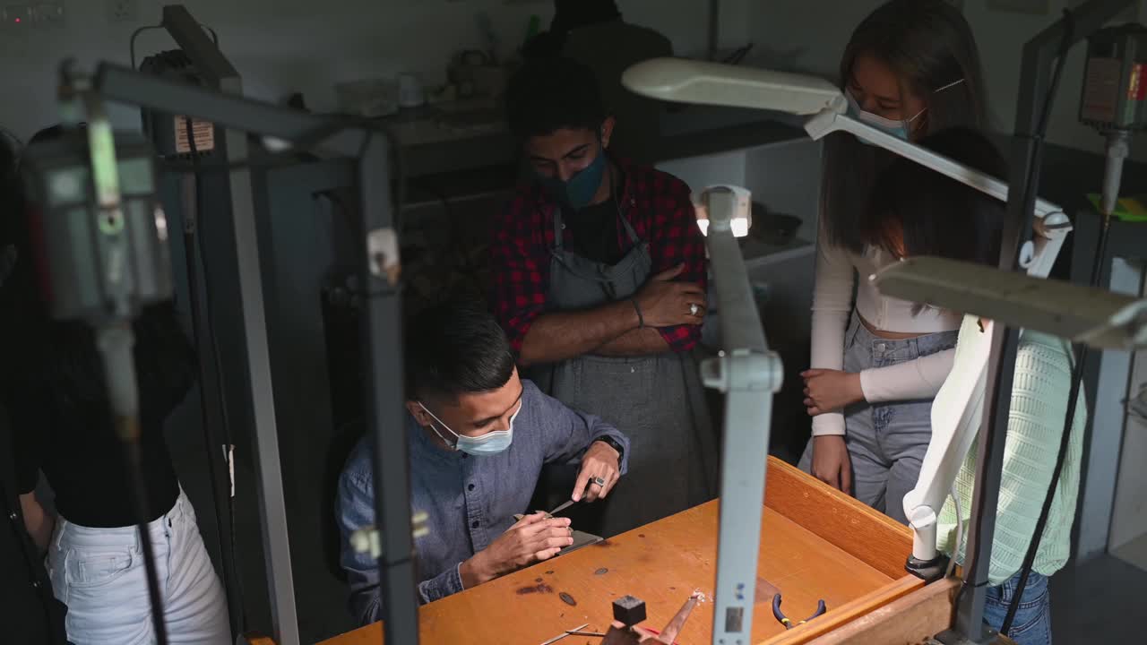 亚洲马来珠宝设计讲师在工作坊工作台上向他的学生展示如何制作珠宝视频素材