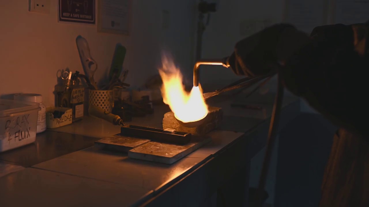 这是中东金匠的手，用火炬在陶罐中熔化银金属视频素材