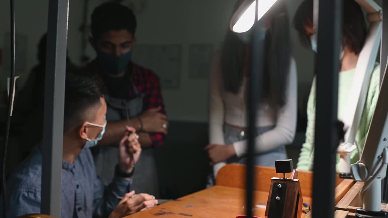 亚洲马来珠宝设计讲师在工作坊工作台上向他的学生展示如何制作珠宝视频素材