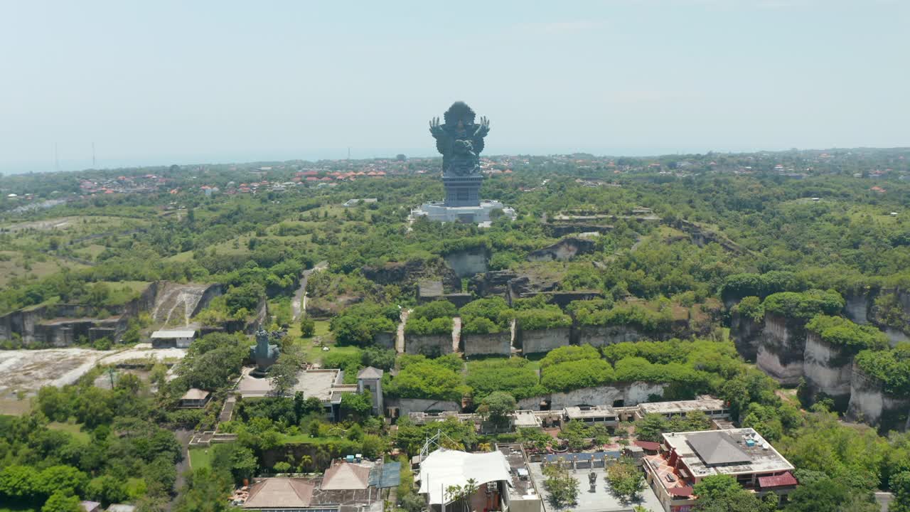 在印度尼西亚巴厘岛的文化公园里，巨大的Garuda Wisnu Kencana雕像。向前移动鸟瞰图的大型宗教纪念碑周围的茂密的绿树在一个公园视频素材