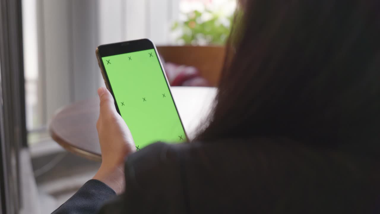 一个女人的手使用一个绿色屏幕的手机的特写视频下载