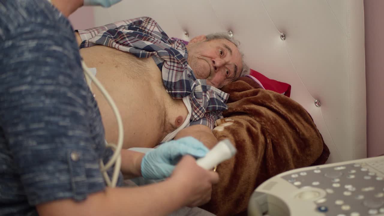 医护护士使用便携式超声机在家为97岁老年男性患者进行超声心脏健康检查和诊断。视频素材