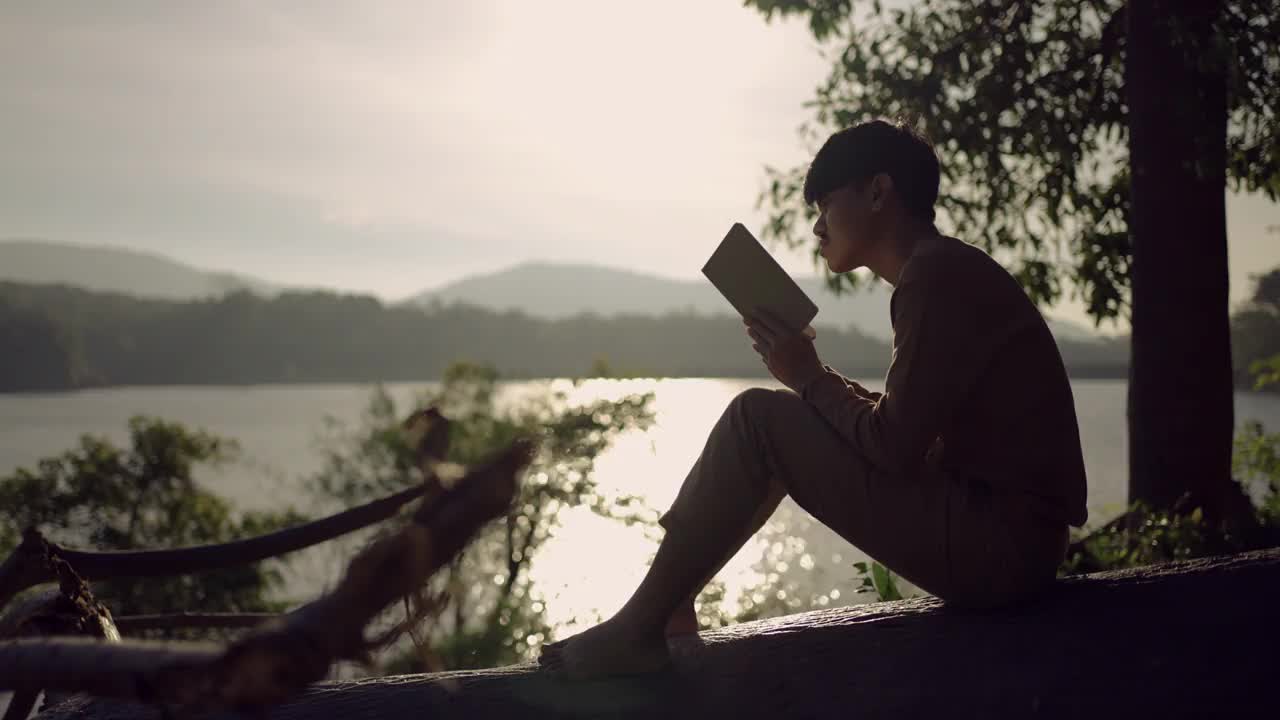 年轻人在湖边看书，放松心情视频下载