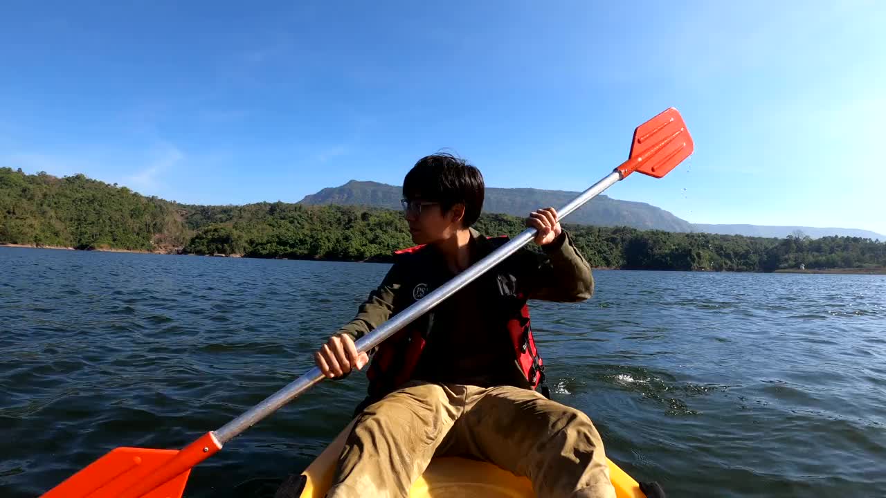 一个年轻人在蓝色的湖面上划皮艇视频素材