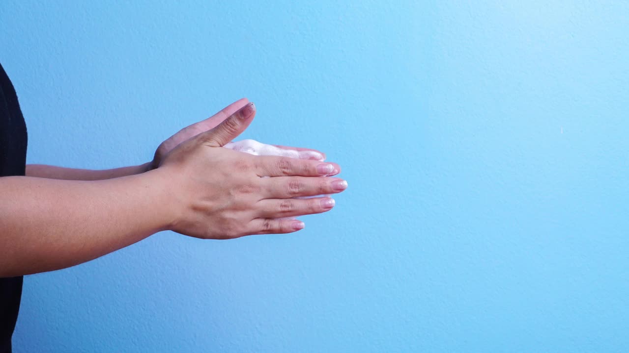 4k:一个女人在蓝色背景下洗手的静止动作视频素材
