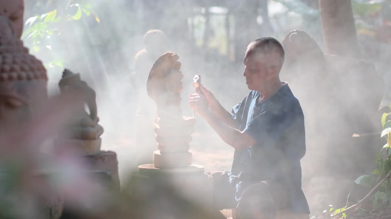 亚洲石雕作品与雕塑看起来像古代风格，他坐在烟雾和一线阳光视频素材