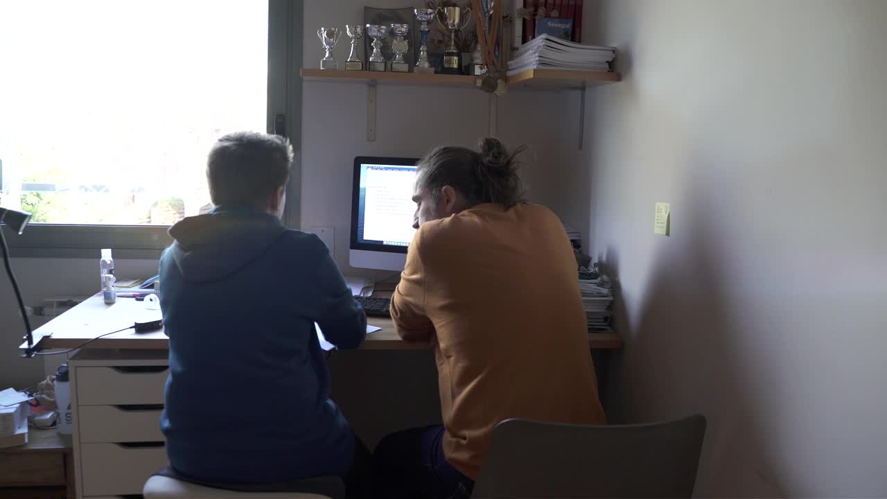 一位父亲在帮助儿子完成家庭作业。视频下载