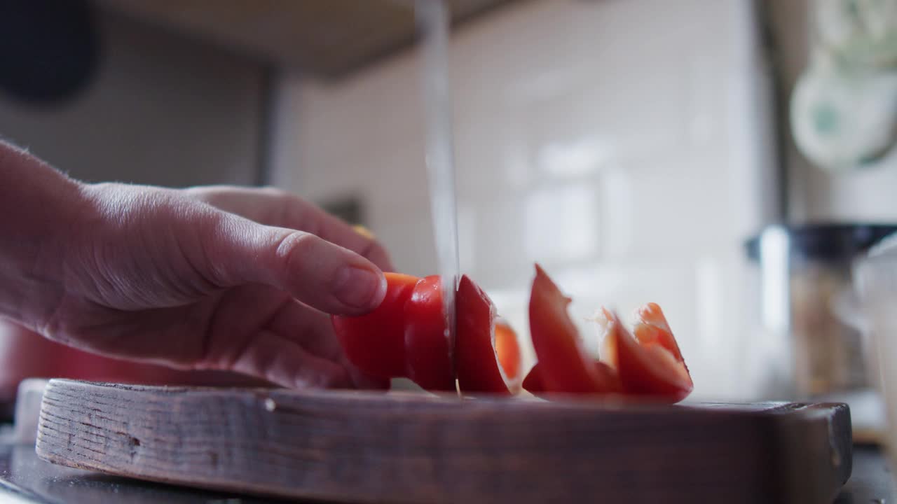 在家庭厨房里，一个面目全非的女人正在切红甜椒视频素材