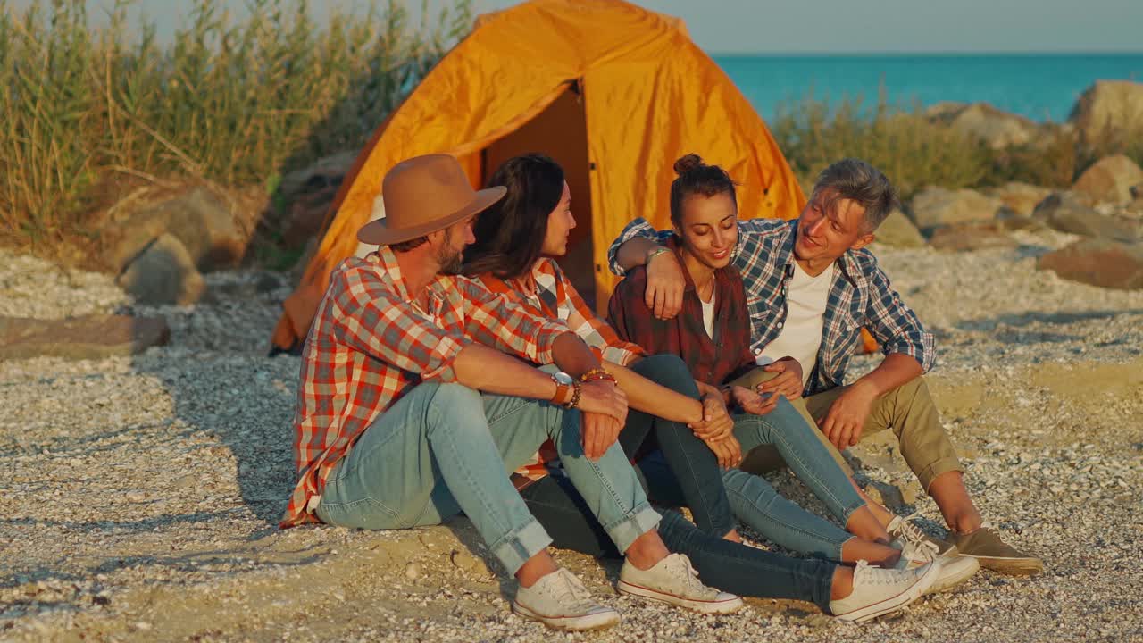 四个朋友坐在海边的日出上视频下载