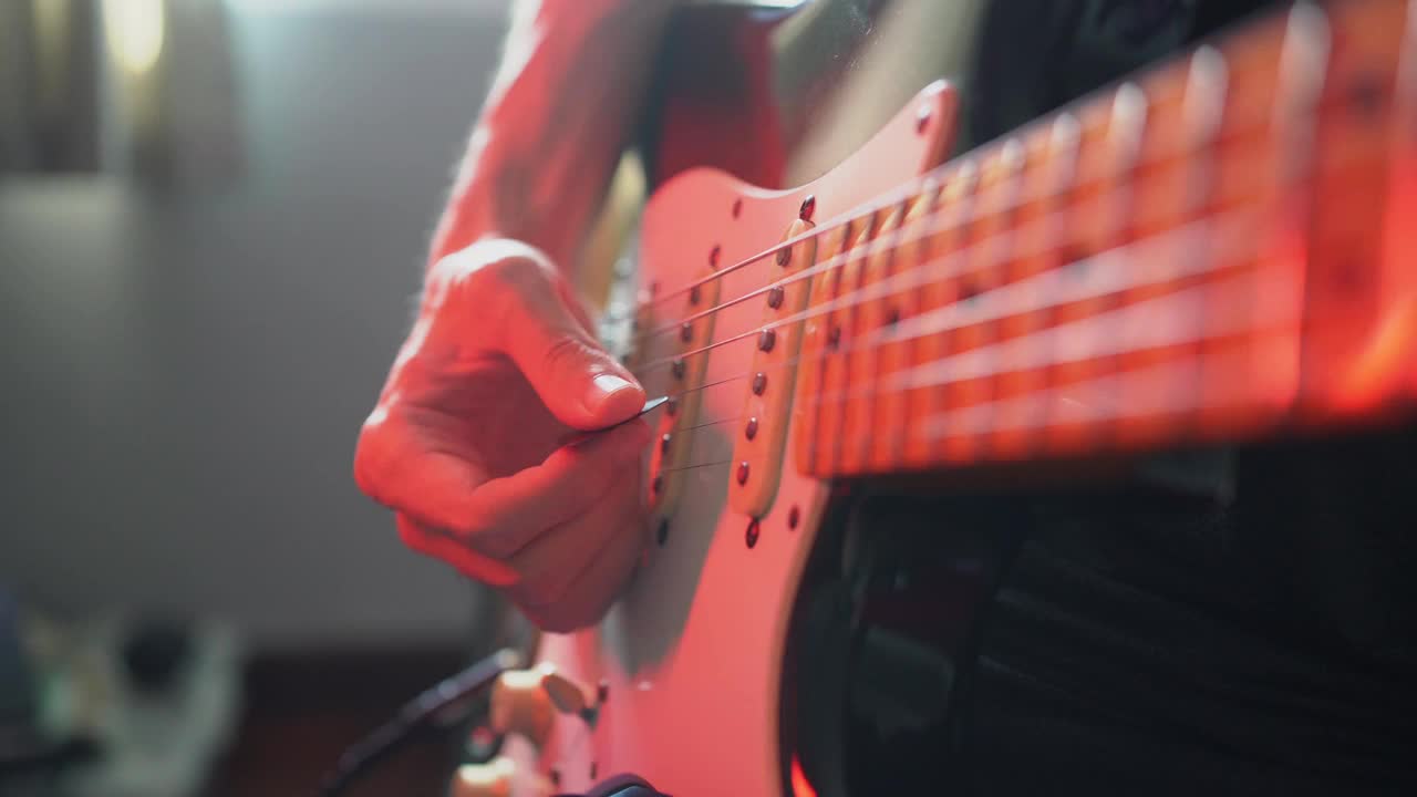 一个男人在一个有彩色灯光的房间里弹电吉他视频素材