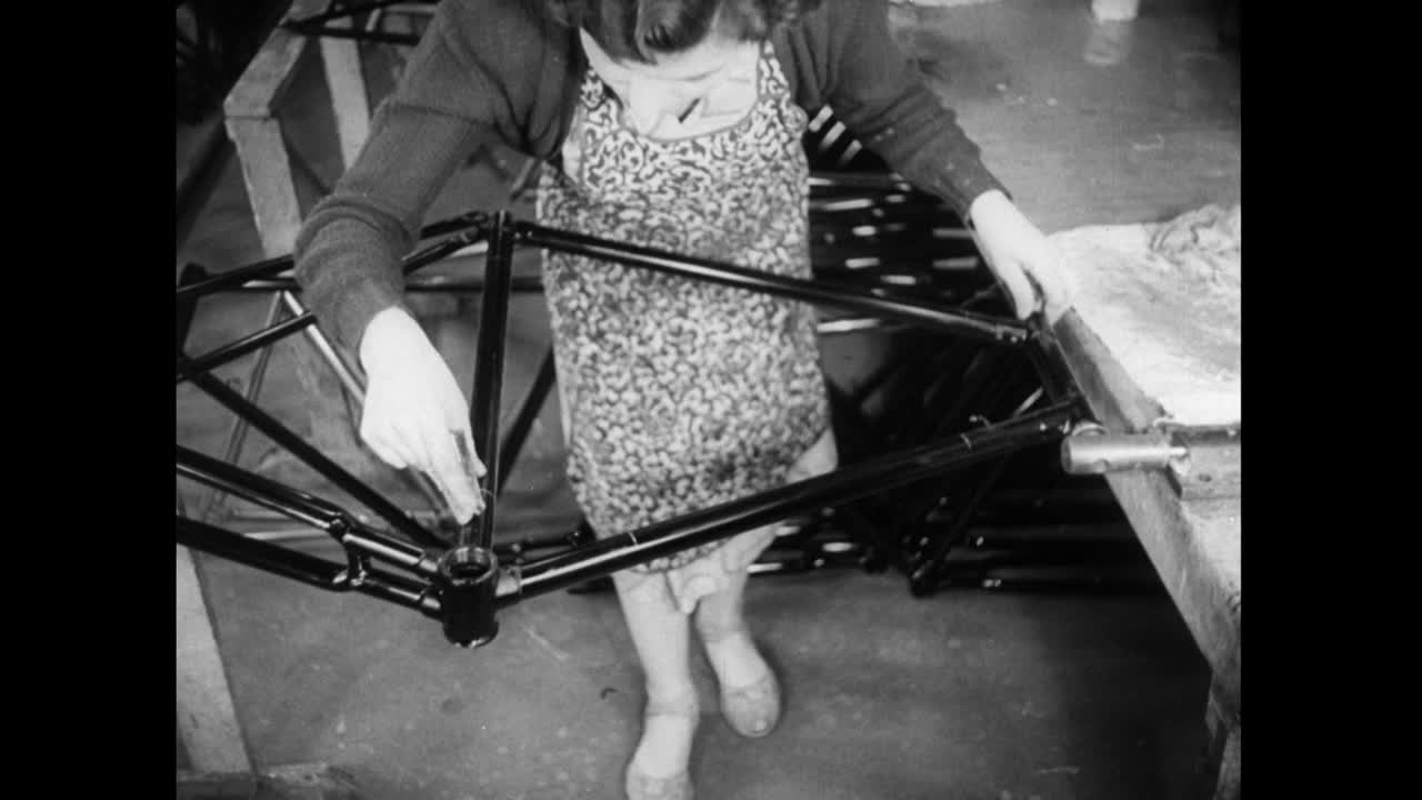 在工厂里，一名妇女在擦拭自行车车架;1952视频素材
