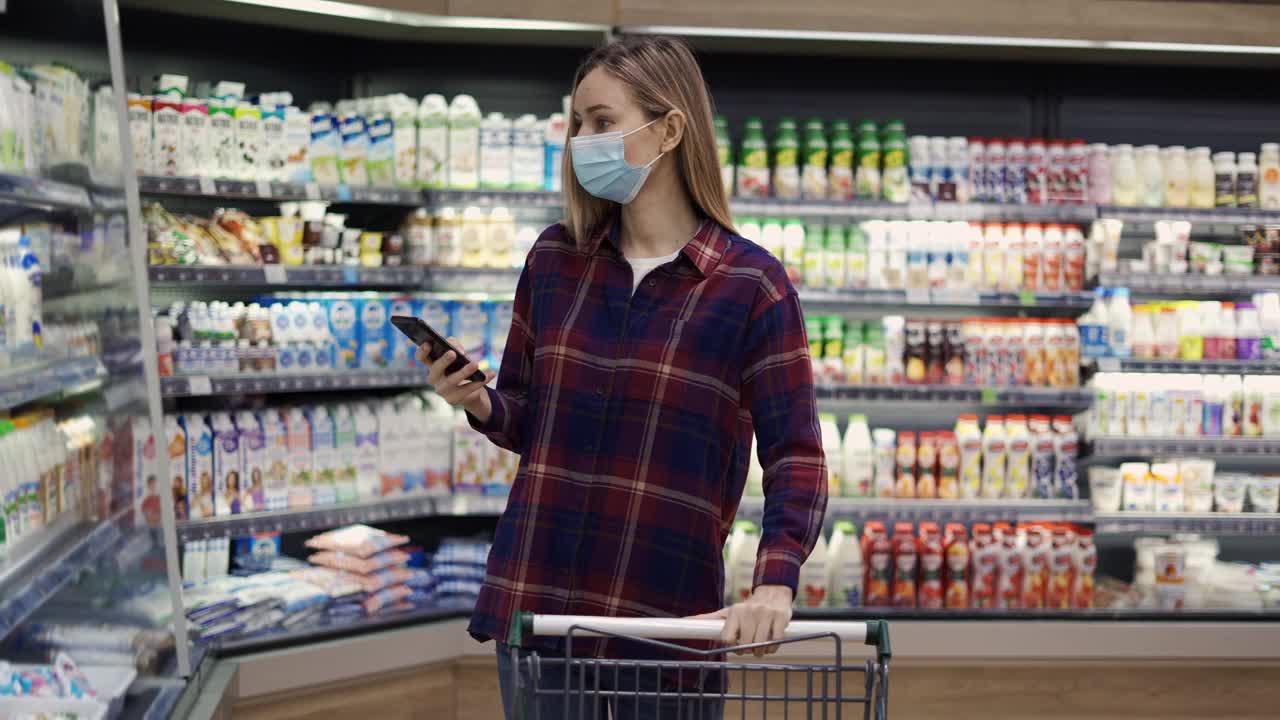 女士在超市用智能手机选购牛奶，查看购物清单视频素材