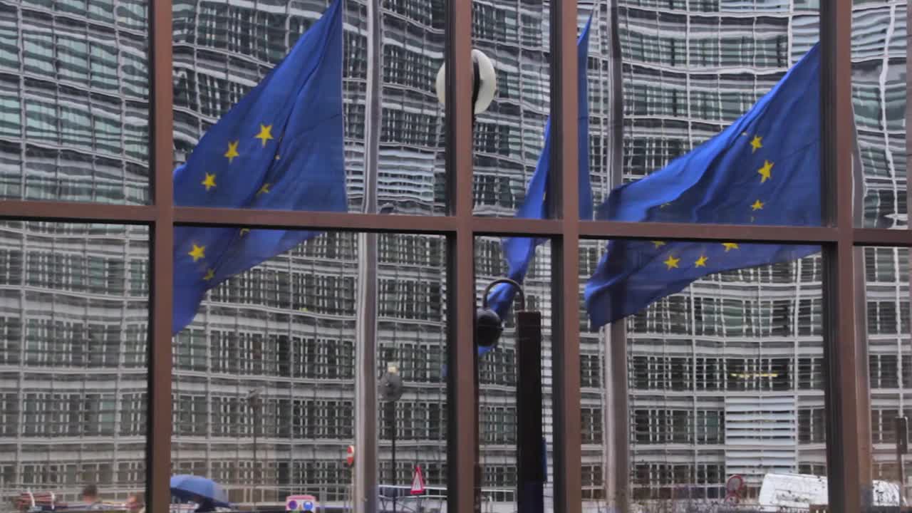 美国国旗和欧盟委员会的标志反射在建筑物的窗户上视频素材