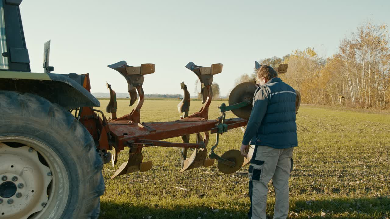 一个成熟的农民在拖拉机旁摆姿势视频素材