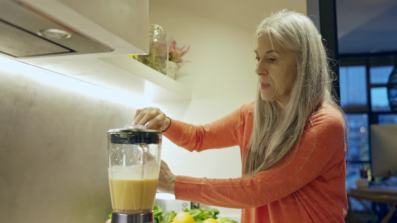 退休妇女在家庭厨房里调配健康饮料视频素材