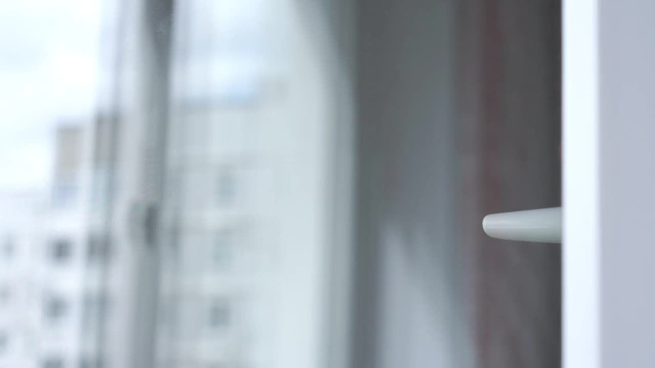 一位戴着一次性口罩的老人向塑料窗户挥手视频素材
