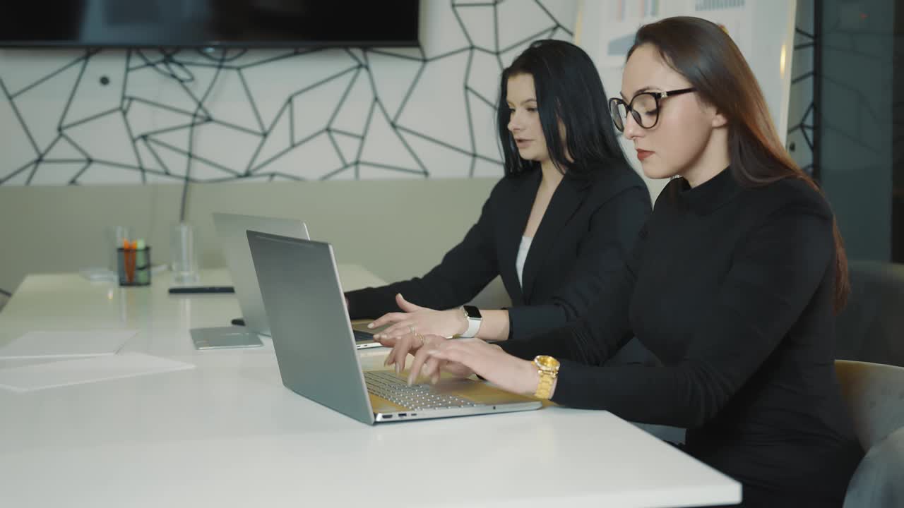 办公室工作流程。对于女性来说，使用笔记本电脑和平板电脑工作。两个办公室职员的肖像视频下载