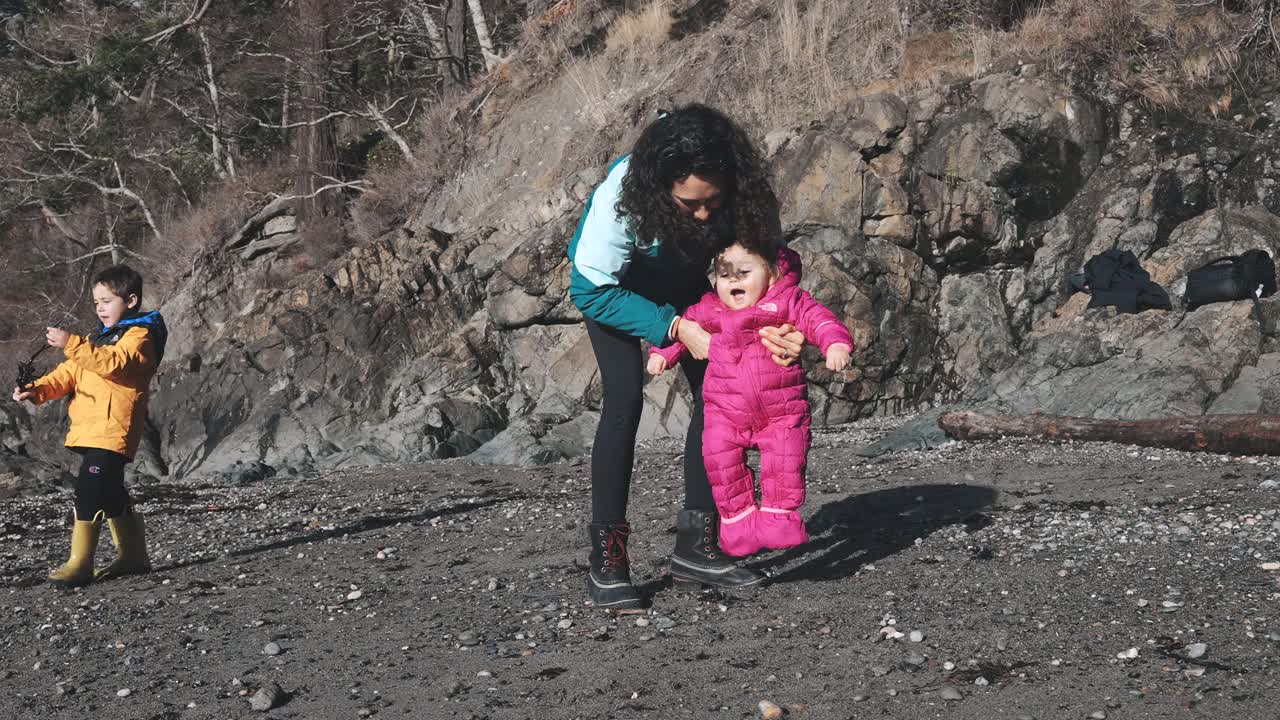 美丽的一岁小女孩在海滩上和她的妈妈一起学习走路视频素材