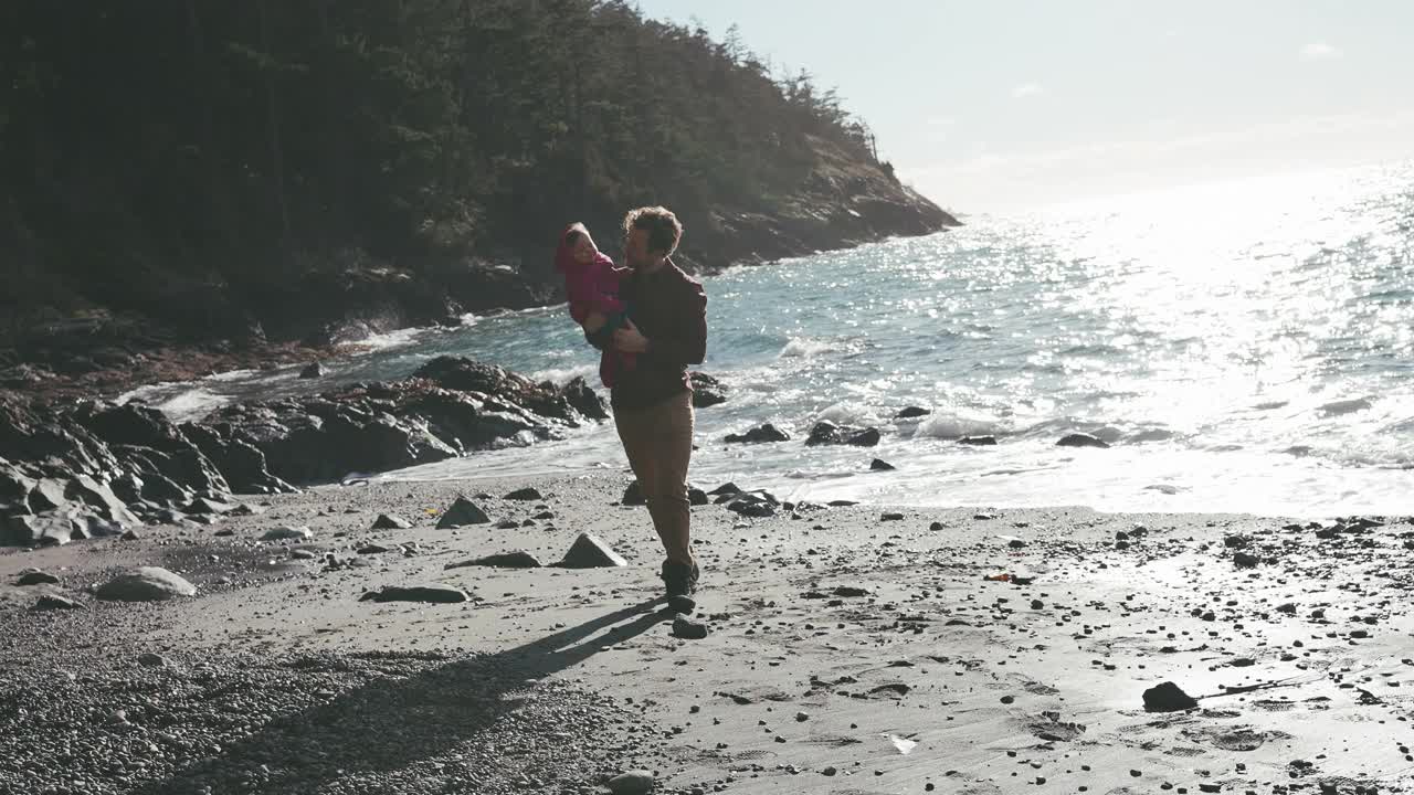 在海滩上，父亲把他的小女儿抛向空中视频素材
