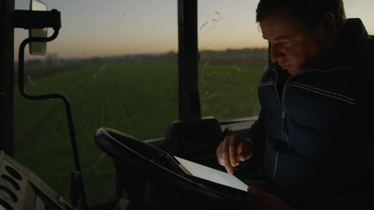 一个成熟的农民在他的拖拉机里使用一个数字平板电脑视频素材