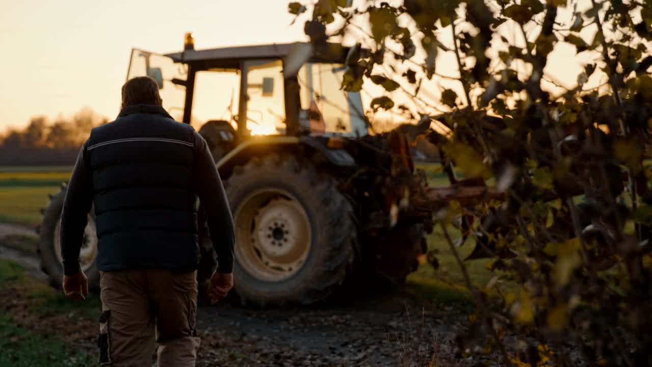 一个面目人非的农民走回田里的拖拉机旁视频素材