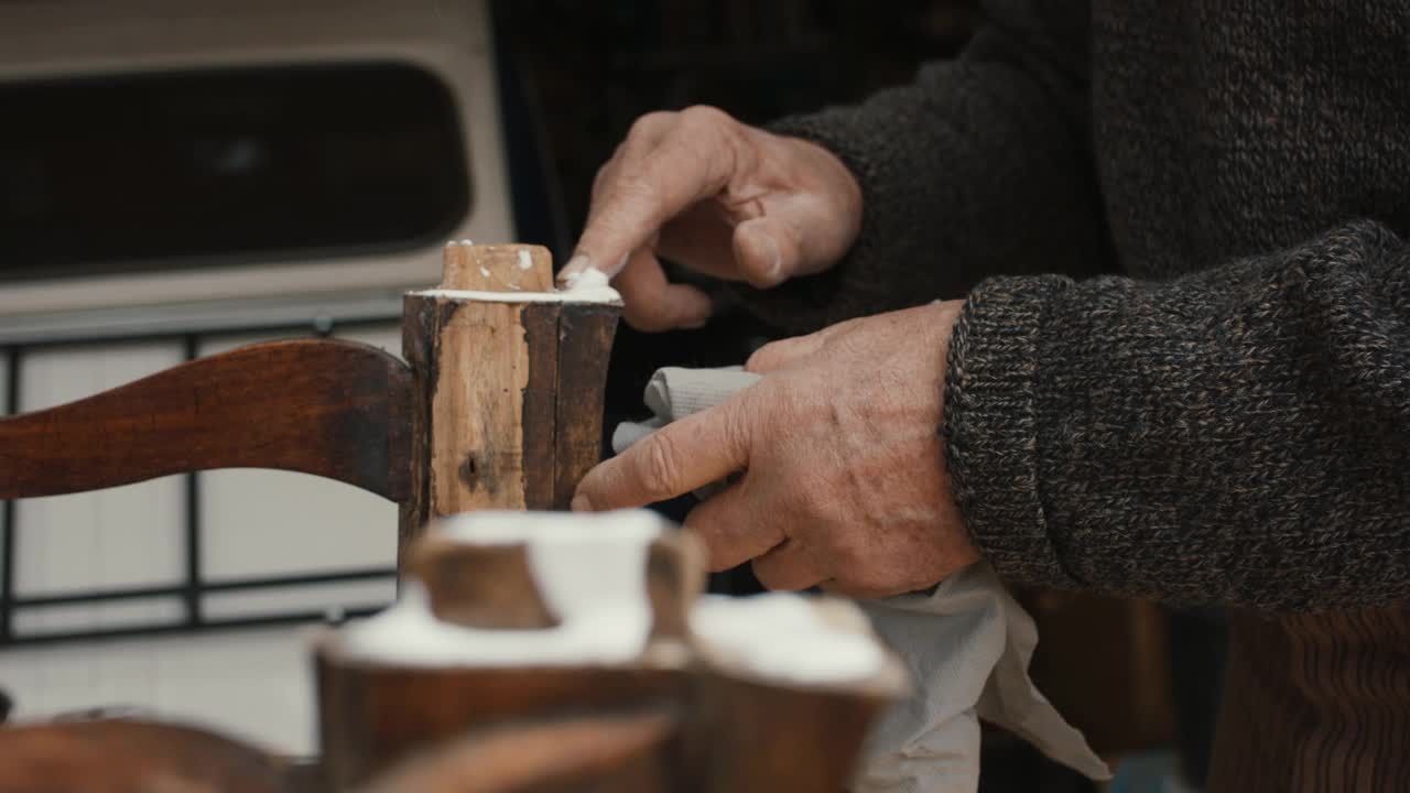 一位老人正在用手指往木椅上涂胶水视频素材